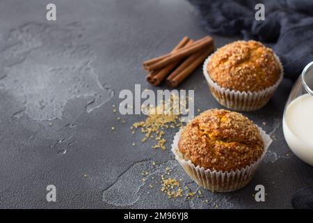 Deliziosi muffin fatti in casa alla zucca con crosta di zucchero piccante con latte su fondo testurizzato nero, spazio Foto Stock