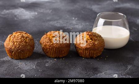 Deliziosi muffin fatti in casa alla zucca con crosta di zucchero piccante con latte su sfondo nero testurizzato, spazio, vista dall'alto Foto Stock