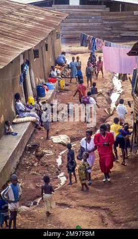 Uganda, persone che camminano lungo una fogna aperta in un quartiere povero di Kampala. Foto Stock