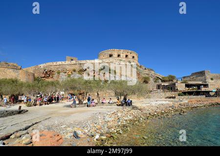 Plaka, Creta, Grecia - 10 ottobre 2022: Turisti non identificati sulla spiaggia presso la vecchia Fortezza Veneziana Spinalonga, precedentemente utilizzato come stazione lebbroso, ora un p Foto Stock