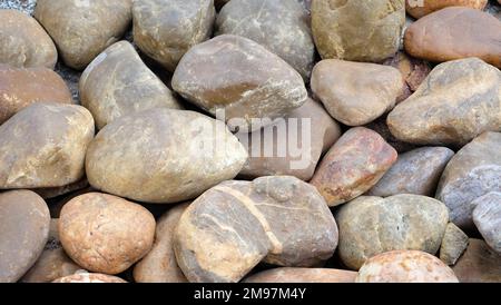 Sfondo di rocce di fiume con angoli arrotondati e una superficie liscia. Foto Stock