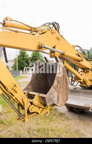 Escavatore con sistema a pistoni idraulici con benna. Lavori di costruzione sul sito industriale. Foto Stock