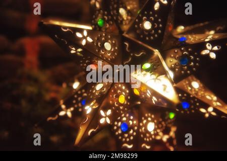 Primo piano di un ornamento illuminato della Stella di Natale appeso ad un albero di Natale Foto Stock