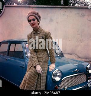 Donna in tuta, cappello e guanti tweed, in posa con un'auto blu. Foto Stock