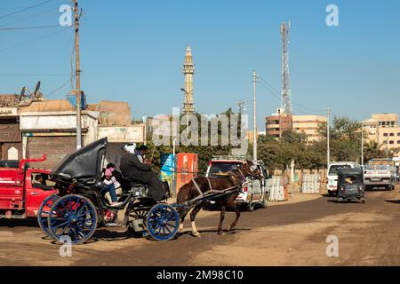 EDFU, EGITTO - 28 Dic 2022. La gente del posto cavalca un cavallo in carrozza utilizzandolo come mezzo di trasporto tradizionale nella folle città di Assuan in Egitto Foto Stock