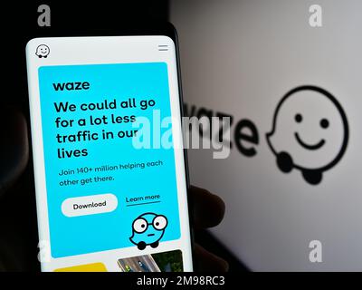 Persona in possesso di smartphone con sito web della società di navigazione israeliana Waze Mobile Ltd. Sullo schermo con logo. Messa a fuoco al centro del display del telefono. Foto Stock