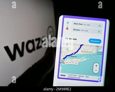 Persona che tiene il telefono cellulare con la pagina web della società di navigazione israeliana Waze Mobile Ltd. Sullo schermo con il logo. Messa a fuoco al centro del display del telefono. Foto Stock