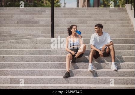 Sportivi seduti sui gradini di cemento dopo l'allenamento all'aperto Foto Stock