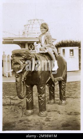 La bambina ed il suo cane giocattolo cavalcano un elefante modello - Cliftonville, Margate, Kent Foto Stock