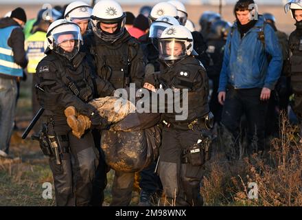 Erkelenz, Germania. 17th Jan, 2023. Gli agenti di polizia trasportano una persona appartenente a un gruppo di manifestanti e attivisti lontano dal bordo della miniera lignite di Garzweiler II opencast. Gli attivisti e gli oppositori del carbone hanno continuato le loro proteste martedì in diverse località della Renania settentrionale-Vestfalia. Credit: Federico Gambarini/dpa/Alamy Live News Foto Stock