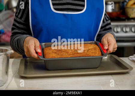 le mani della donna tengono una frittella che ha appena cotto in cucina Foto Stock