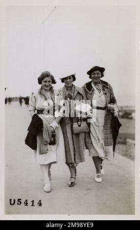 Tre Signore che hanno un momento di festa in Margate, Kent, Inghilterra. Ognuno ha sciarpe mutlipe, borse, cappelli, ombrelli e guanti!!! Foto Stock