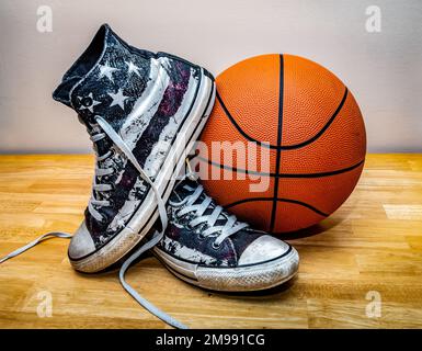 Basket e paio di scarpe da basket classiche in tela su parquet. Foto Stock