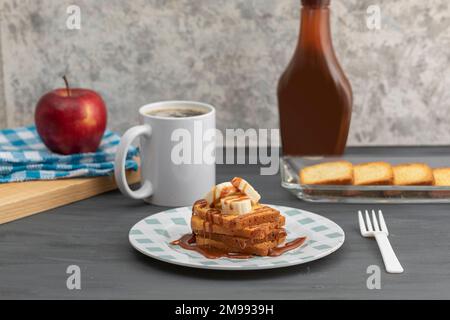 Colazione a base di pane tostato con cajeta e banana accompagnati da una tazza di caffè e mela. Foto Stock