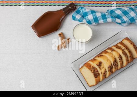 vista dall'alto di un pane di noce su una tovaglia blu accanto ad un bicchiere di latte e cajeta. Foto Stock