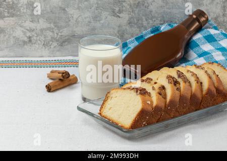 Pane di noce a fette su un piatto con un bicchiere di latte e cajeta sullo sfondo. Foto Stock