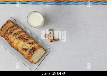 Vista dall'alto di un pane di noce a fette su un piatto di vetro con un bicchiere di latte. Foto Stock