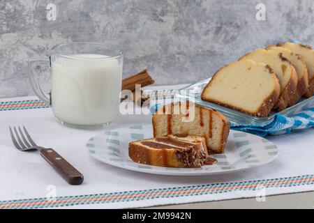 due fette di pane di noce con cajeta su un tavolo accompagnato da un bicchiere di latte. Foto Stock