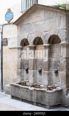 Txakurraren iturria, Bilbao, Paesi Baschi. Tre fontane in una struttura in pietra con archi sopra e un segno di strada ornato a sinistra. Foto Stock