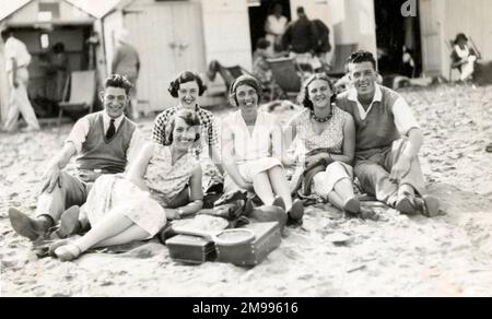 Festa in spiaggia di fronte a capanne sulla spiaggia, Paignton, Devon. Foto Stock