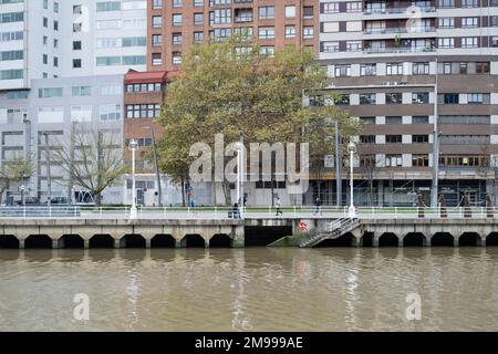 Si affaccia sul fiume Nervíon a Bilbao, Paesi Baschi, con edifici dietro e un'arte di strada piastrellata Invader sul bordo che conduce alla riva Foto Stock