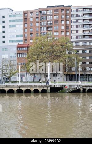Si affaccia sul fiume Nervíon a Bilbao, Paesi Baschi, con edifici dietro e un'arte di strada piastrellata Invader sul bordo che conduce alla riva Foto Stock