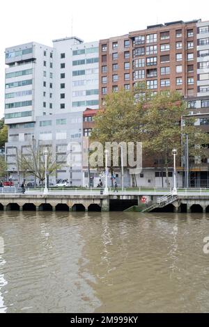 Si affaccia sul fiume Nervíon a Bilbao, Paesi Baschi, con edifici dietro e un'arte di strada piastrellata Invader sul bordo che conduce alla riva Foto Stock