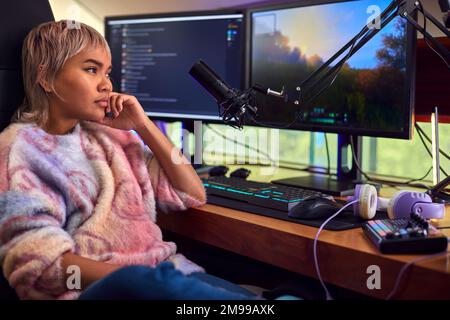 Donna stanca e infelice Gaming a casa seduto alla scrivania con più monitor Foto Stock