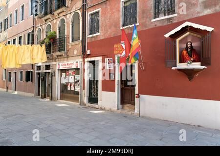 Lenzuola gialle appese su una linea per asciugarsi, accanto a un club comunista e una cappella di Gesù Cristo sul muro. Foto Stock