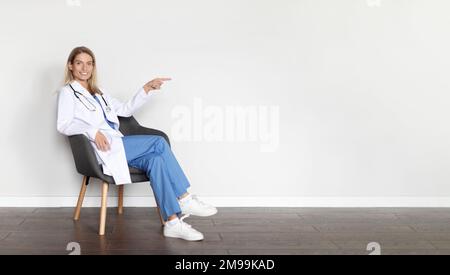 Offerta sanitaria. Medico femminile seduto in sedia e che indica lo spazio copia Foto Stock