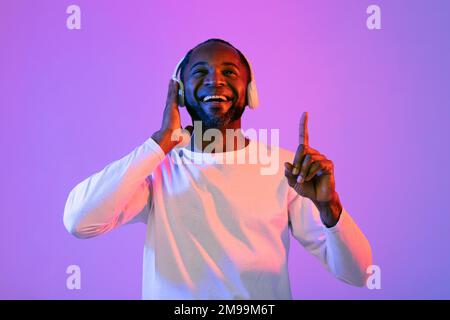 Gioioso uomo nero che ascolta musica e sorridente Foto Stock