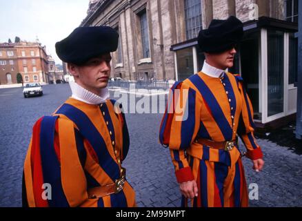 Due Guardie Svizzere Pontificie si trovano a Roma, in Città del Vaticano. Indossano colorate uniformi rinascimentali di blu, giallo e rosso Foto Stock