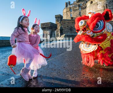 Giovani ragazze cinesi che indossano orecchie di coniglio intrattenuti da danzatori drago per celebrare il Capodanno cinese, (anno del coniglio), Castello di Edimburgo, Scozia, Regno Unito Foto Stock