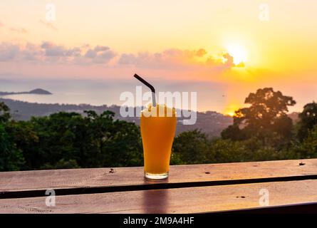 Frullato di Mango sullo sfondo del bellissimo tramonto e del mare dal punto di vista dell'isola di Koh Samui, Thailandia. Foto Stock