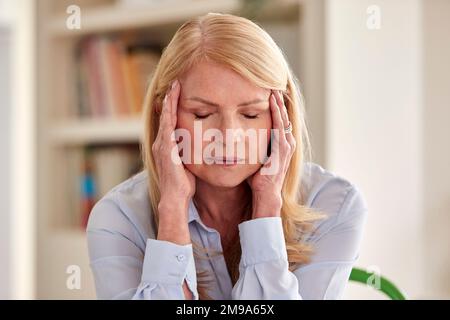 Donna matura in menopausa a casa che soffre di mal di testa Foto Stock