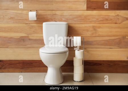 Vaso in ceramica e supporti con rotoli di carta vicino a pareti in legno Foto Stock