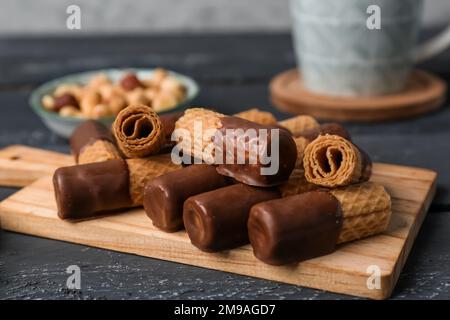 Tavola di deliziosi cialde, ciotola di nocciole e tazza su fondo grunge scuro Foto Stock