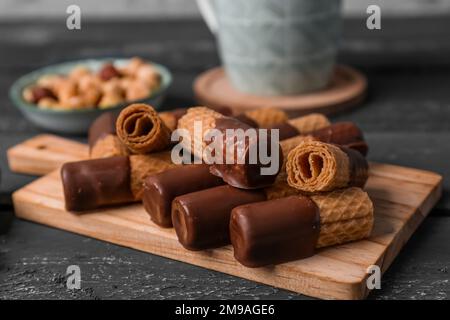 Tavola di deliziosi cialde, ciotola di nocciole e tazza su fondo grunge scuro Foto Stock