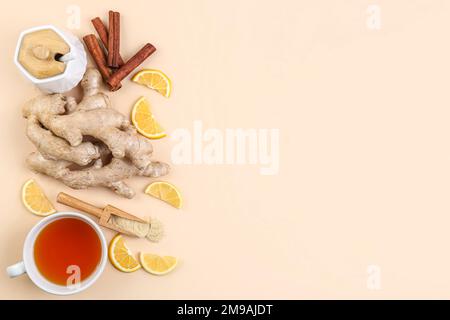 Radici di zenzero, tazza di tè nero, fettine di limone e cannella su sfondo beige Foto Stock