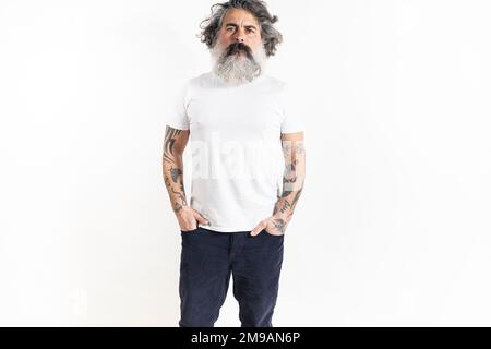 Posa bella tatuata uomo bearded in pantaloni corduroy e bianco premium raffinata t-shirt estiva, isolato su sfondo bianco Foto Stock