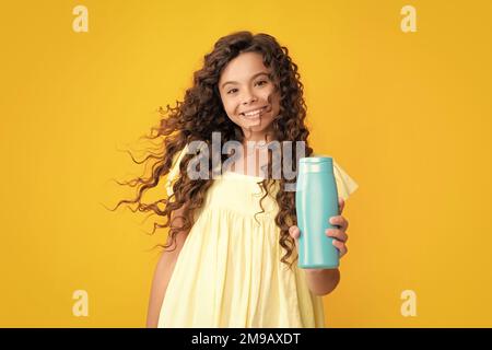 Felice ritratto di ragazza teen bambino con shampoos balsami e gel doccia. Cura dei capelli lunghi dell'adolescente. Prodotto cosmetico di presentazione, bottiglia di shampoo Foto Stock