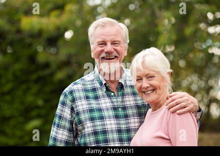 Ritratto di amorevole pensionato Senior Couple abbracciando all'aperto in campagna o giardino insieme Foto Stock