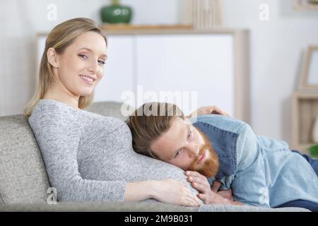 l'uomo appoggia la testa sul pancino incinta Foto Stock