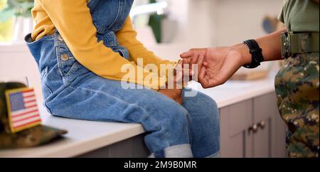 Amando la madre americana dell'esercito nella sede uniforme sul permesso che tiene le mani con la figlia in cucina della famiglia Foto Stock