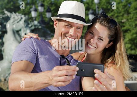 giovane coppia sorridente che prende selfie all'aperto Foto Stock