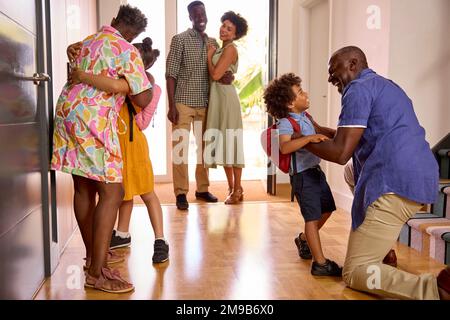 Famiglia Multi-generazione con nonni saluto i nipoti in corridoio a casa Foto Stock