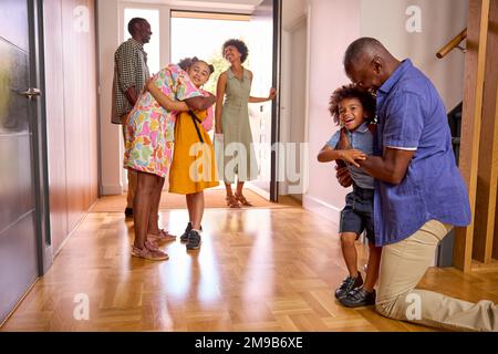 Famiglia Multi-generazione con nonni saluto i nipoti in corridoio a casa Foto Stock