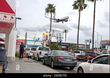 Un aereo che atterra all'aeroporto internazionale di Los Angeles (LAX) passa sopra le auto allineate per l'ordine in un ristorante in-N-out Burger a Los Angeles, California, USA Foto Stock