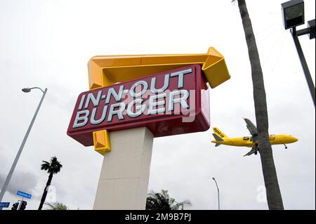Un aereo giallo Spirit Airlines sta per atterrare all'aeroporto di Los Angeles, proprio accanto a un ristorante fast food in-N-out Burger a Los Angeles, California Foto Stock