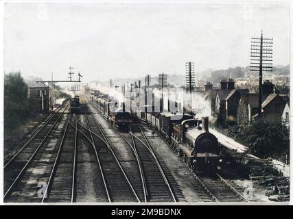 Un treno merci attende su un binario per lasciare passare il treno passeggeri, mentre un terzo treno si avvicina attraverso la stazione di Redhill, Surrey. Foto Stock